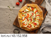 Top view, copy space. Homemade savory galette with vegetables, wheat pie with tomatoes, zucchini. Стоковое фото, фотограф Natalia Gdovskaia / Фотобанк Лори