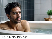Depressed crazy man mental health in bathtub in bathroom at home looking at camera. Problem person showing human emotions. Concept apathy, anxiety, illness, trouble, creative decline. Copy space. Стоковое AI-изображение, AI-художник Aleksandr Golubev / Фотобанк Лори
