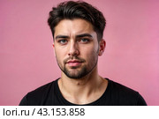 Dissatisfied young man looking unpleasantly away, expresses aversion, smirking at pink background. Guy in black t-shirt scared, negative face expressions concept. Advertising. Copy text space. Стоковое AI-изображение, AI-художник Aleksandr Golubev / Фотобанк Лори