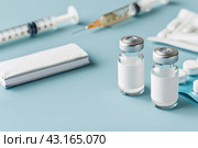 Syringe and glass vial on blue background table. Medical Vials group, needles, ampoules, bottle with medicines or vaccine. Disease treatment. Creative Banner. Anti-aging beauty injections. Vaccination. Стоковое AI-изображение, AI-художник Марина Демидюк / Фотобанк Лори