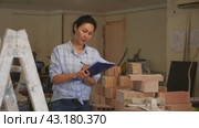 Asian woman with documents in her hands stands in the middle of renovated room in a cottage. Стоковое видео, видеограф Яков Филимонов / Фотобанк Лори