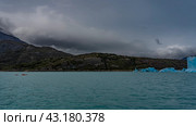 Canoes with tourists sail along the turquoise lake to the glacier. A wall of blue ice, icebergs in the water. Coastal rocky mountains against a cloudy sky. Perito Moreno. El Calafate. Argentina. (2023 год). Стоковое фото, фотограф Вера Ивановна Кубарева / Фотобанк Лори