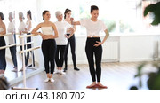 Female teacher leading ballet class, showing graceful dance movements for women of different ages standing at barre, emphasizing discipline in studio. Стоковое видео, видеограф Яков Филимонов / Фотобанк Лори