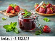 A jar of homemade strawberry, healthy jam with mint on a black background. Conservation and harvesting in summer. Стоковое AI-изображение, AI-художник Photojuli / Фотобанк Лори