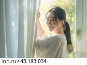 Young asian woman unveil curtain and looking out of window in the morning. Beautiful girl nearly window after waking up fully rested and open curtains. Start the new day with happiness. Relax, resting. Стоковое AI-изображение, AI-художник Марина Демидюк / Фотобанк Лори