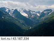 View of the Alibek Gorge, the Alibek River and the mountains of the Main Caucasian Ridge, opening from the upper station of the cable car system of the Dombay ski resort, Karachay-Cherkessia, Russia. Стоковое фото, фотограф Ula Ulachka / Фотобанк Лори
