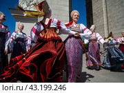 Девушки в русских национальных костюмах водят хороводы и поют народные песни у арки Центрального входа на территорию выставочного комплекса ВДНХ в городе Москве, Россия (2024 год). Редакционное фото, фотограф Николай Винокуров / Фотобанк Лори