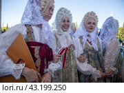 Девушки в русских национальных костюмах водят хороводы и поют народные песни у арки Центрального входа на территорию выставочного комплекса ВДНХ в городе Москве, Россия (2024 год). Редакционное фото, фотограф Николай Винокуров / Фотобанк Лори