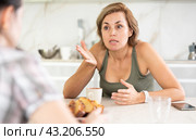 Upset middle-aged woman talking sadly while drinking tea in the kitchen. Стоковое фото, фотограф Яков Филимонов / Фотобанк Лори