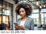 A businesslike dark-skinned African-American woman with curly hair. She is dressed in a casual jacket. In the hands of a smartphone. A businesswoman looks at her mobile phone. Стоковое AI-изображение, AI-художник Photojuli / Фотобанк Лори