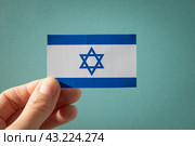 Израильский флаг в руке на бирюзовом фоне. Стоковое фото, фотограф Дорощенко Элла / Фотобанк Лори