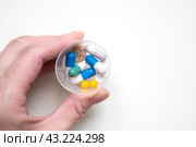 Таблетки, капсулы и гранулы в контейнере в человеческой руке на светлом фоне. Суточная доза лекарств. Витамины для лечения и профилактики. Стоковое фото, фотограф Дорощенко Элла / Фотобанк Лори