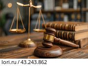Symbols of justice represented by a wooden judge's gavel and golden scales of justice located on a wooden table in a legal office. Stacks of leather-bound law books are visible in the background, emphasizing the professional atmosphere. The image conveys a sense of justice, law and order, ideal for use on legal websites or legal-related articles. Стоковое AI-изображение, AI-художник Анна Кривицкая / Фотобанк Лори