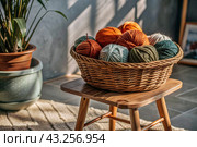 Balls of yarn in a wicker basket on a wooden stool. Needlework, textiles, knitting. Winter season, small business, handmade clothes. Стоковое AI-изображение, AI-художник Photojuli / Фотобанк Лори