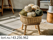 Balls of yarn in a wicker basket on a wooden stool. Needlework, textiles, knitting. Winter season, small business, handmade clothes. Стоковое AI-изображение, AI-художник Photojuli / Фотобанк Лори
