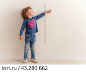 Child Measuring Height Against Wall. Стоковое AI-изображение, AI-художник Кирилл Черезов / Фотобанк Лори