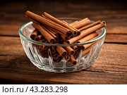 Ceylon cinnamon sticks in glass plate on wooden board, rustic style. Still life natural food of sri lankan cinnamon sticks on table at grey wall. Delicious tasty healthy concept. Copy ad text space. Стоковое AI-изображение, AI-художник Aleksandr Golubev / Фотобанк Лори