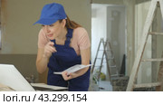 Woman in blue overalls checking completed construction work on the drawing. Стоковое видео, видеограф Яков Филимонов / Фотобанк Лори