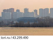 Вечерний городской пейзаж. Вид на спортивный ледовый дворец и современные жилые многоэтажные дома. Город Новосибирск, Новосибирская область, Сибирь, Россия. На переднем плане река Обь. Большой сибирский город. Стоковое фото, фотограф Андрей Степанов / Фотобанк Лори