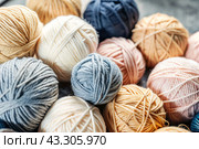 The background is made of balls of wool yarn . Needlework, textiles, knitting. Winter season, small business, handmade clothes. Стоковое AI-изображение, AI-художник Photojuli / Фотобанк Лори
