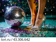 Women's legs in luxurious shiny pumps with heels at a party or disco on the background of a silver mirrored disco ball. The queen of the dance floor. Стоковое AI-изображение, AI-художник Photojuli / Фотобанк Лори