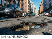 The terrible condition of the roads. A hole in the asphalt on a city street. Road repairs. A city street of poor quality. Стоковое AI-изображение, AI-художник Photojuli / Фотобанк Лори