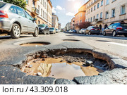 The terrible condition of the roads. A hole in the asphalt on a city street. Road repairs. A city street of poor quality. Стоковое AI-изображение, AI-художник Photojuli / Фотобанк Лори