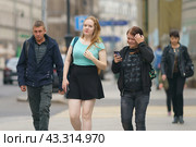 Moscow, Russia - August 13, 2021: Street photography. Youth on the city street in summer day. Lifestyle concept. Portraits of happy friends. One of them tells something. Both glowing with happiness. Редакционное фото, фотограф YuryKara / Фотобанк Лори
