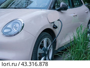 An electric car, GWM ORA 03, is parked on the street and is charging (2024 год). Редакционное фото, фотограф Константин Григорьев / Фотобанк Лори
