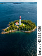 Aerial view landscape of archipelago of islands with lighthouse in Gulf of Finland, skyline at blue sky background. Amazing natural wild scenery view of Scandinavian nature. Copy ad text space. Стоковое AI-изображение, AI-художник Aleksandr Golubev / Фотобанк Лори
