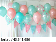 A delightful party decoration includes a grouping of pink and blue balloons tied in a row. Стоковое AI-изображение, AI-художник Юрий Поздников / Фотобанк Лори