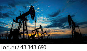Oil pumps on the background of a dark sky and sunset. Copy space. Стоковое AI-изображение, AI-художник Ярославский Максим / Фотобанк Лори