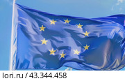 On a pole, a blue rectangular flag with yellow stars waves in the wind under the sky. Стоковое AI-видео, аниматор Юрий Поздников / Фотобанк Лори