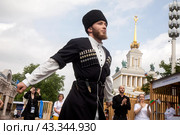 Мужчина в традиционном национальном костюме танует кавказский танец у стенда Карачаево-Черкесской Республики на выставке-форуме "Россия" на ВДНХ в городе Москве, Россия (2024 год). Редакционное фото, фотограф Николай Винокуров / Фотобанк Лори