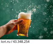 Hand Holding a Splashing Beer Glass. Стоковое AI-изображение, AI-художник Кирилл Черезов / Фотобанк Лори