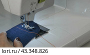 Швея шьет джинсовую ткань. Шов на ткани. Крупный план. Seamstress sews denim. A seam on the fabric. Close-up. Стоковое видео, видеограф Александр Собко / Фотобанк Лори