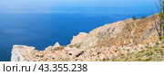 Baikal Lake in summer. Panoramic view of famous rocky cape Sagan-Khushun or Three Brothers on Olkhon Island. A group of tourists travels along rock and take pictures of beautiful landscape on sunny day (2023 год). Стоковое фото, фотограф Виктория Катьянова / Фотобанк Лори
