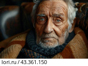 A close-up of an elderly man with pronounced wrinkles and a deep gaze, sitting in a chair. His face conveys a wealth of life experience and wisdom. The man is dressed in warm clothes, consisting of a knitted scarf and a cozy sweater, which emphasizes the atmosphere of comfort and care. The background is slightly blurry, but one can assume that he is in a cozy environment, perhaps a nursing home or a cozy home. Стоковое AI-изображение, AI-художник Анна Кривицкая / Фотобанк Лори