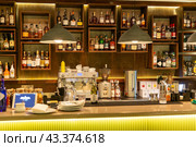 Bar counter in a modern restaurant. Bottles of alcohol behind the bar (2023 год). Редакционное фото, фотограф Евгений Ткачёв / Фотобанк Лори