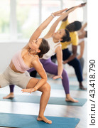 Young woman coach and students perform utkata konasana during training in studio. Стоковое фото, фотограф Яков Филимонов / Фотобанк Лори