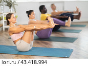 Young woman coach and students perform Paripurna Navasana during training in studio. Стоковое фото, фотограф Яков Филимонов / Фотобанк Лори