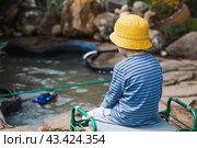 A 5-year-old boy in a yellow panama hat launches a radio-controlled boat in a pond. Children's fun and street games. Child's leisure time. Стоковое фото, фотограф Photojuli / Фотобанк Лори