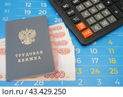 Трудовая книжка, калькулятор и российские деньги лежат на листах календаря. Стоковое фото, фотограф Цибаев Алексей / Фотобанк Лори