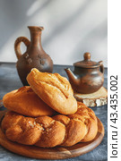 Different types of bread - kalacha, hala - braided loaf with coarse salt. Bread on table with kettle and jug, prepared for consumption. Assortment of handmade bread. Стоковое фото, фотограф Оксана Медведева / Фотобанк Лори