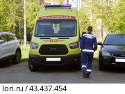 Сотрудник скорой помощи идёт к машине скорой  реанимационной помощи во дворе жилого дома. Стоковое фото, фотограф Людмила Ефимова / Фотобанк Лори