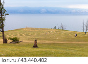 Baikal Lake in summer. Coast of Olkhon Island. Tourists walk in circles through magical labyrinth of stones near village of Kharantsy, landmark of the island. Summer travel and hikes around Olkhon Island. Стоковое фото, фотограф Виктория Катьянова / Фотобанк Лори