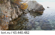 Video of Baikal Lake on Autumn. Coast of Olkhon Island on October. Clea transparent water of Small Sea. Beautiful autumn landscape with yellowed bushes on steep cliffs. Natural background. Travel and outdoor recreation. Стоковое видео, видеограф Виктория Катьянова / Фотобанк Лори