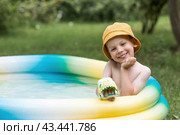 It's a hot day. A cute boy is swimming and splashing in the pool. A happy little boy smiles at the camera. Splashes of water are flying in all directions. The concept of summer holidays with children. Стоковое фото, фотограф Photojuli / Фотобанк Лори