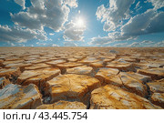 Lifeless desert with cracked earth under bright sunlight. The ground is covered with many cracks and looks dried out from the prolonged heat. On the horizon, the sky is clear and blue, with small white clouds providing a contrast to the harsh land. The sun's rays break through the clouds, illuminating cracks and giving the scene drama and a sense of extreme heat and drought. Стоковое AI-изображение, AI-художник Анна Кривицкая / Фотобанк Лори
