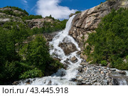 View of the Alibek waterfall formed by the fall of the Jalovchatka River from the Alibek glacier on a sunny summer day, Dombay, Karachay-Cherkessia, Russia. Стоковое фото, фотограф Ula Ulachka / Фотобанк Лори